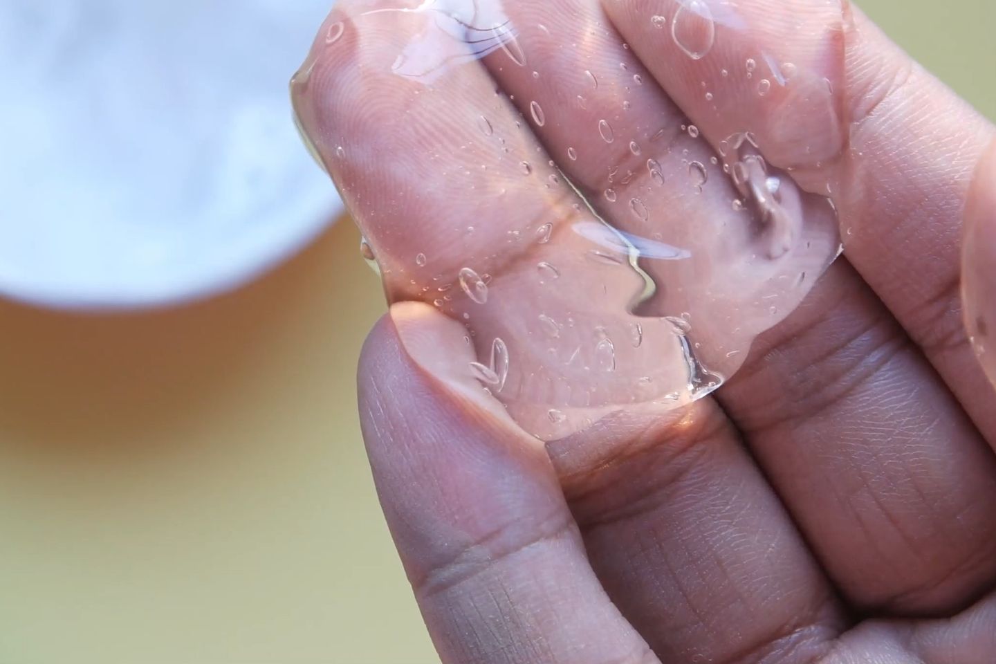 Klares Aloe-Vera-Blattgel in einer offenen Hand, daneben ein Blatt